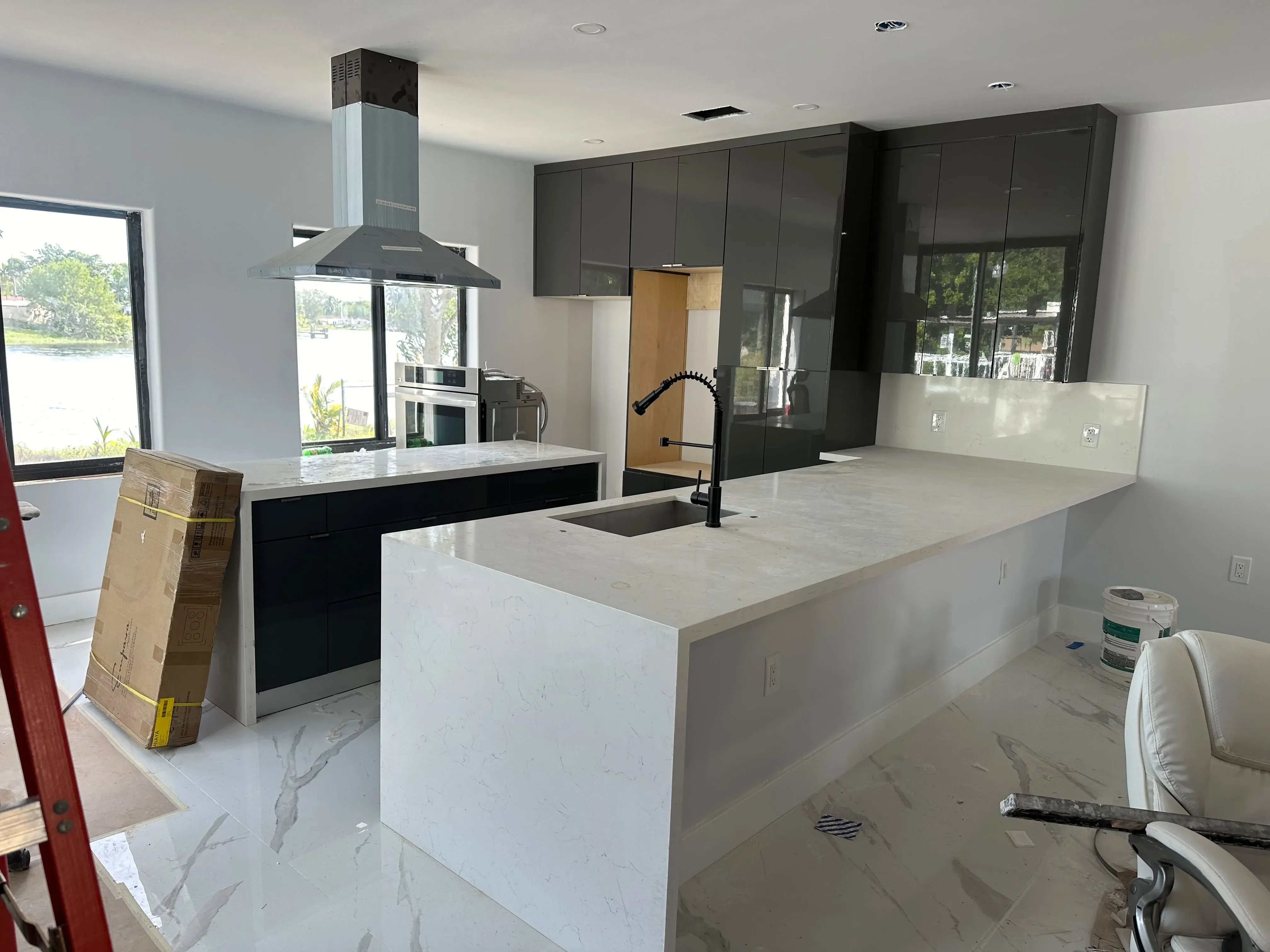 Black and white kitchen cabinets with a waterfall peninsula and range hood
