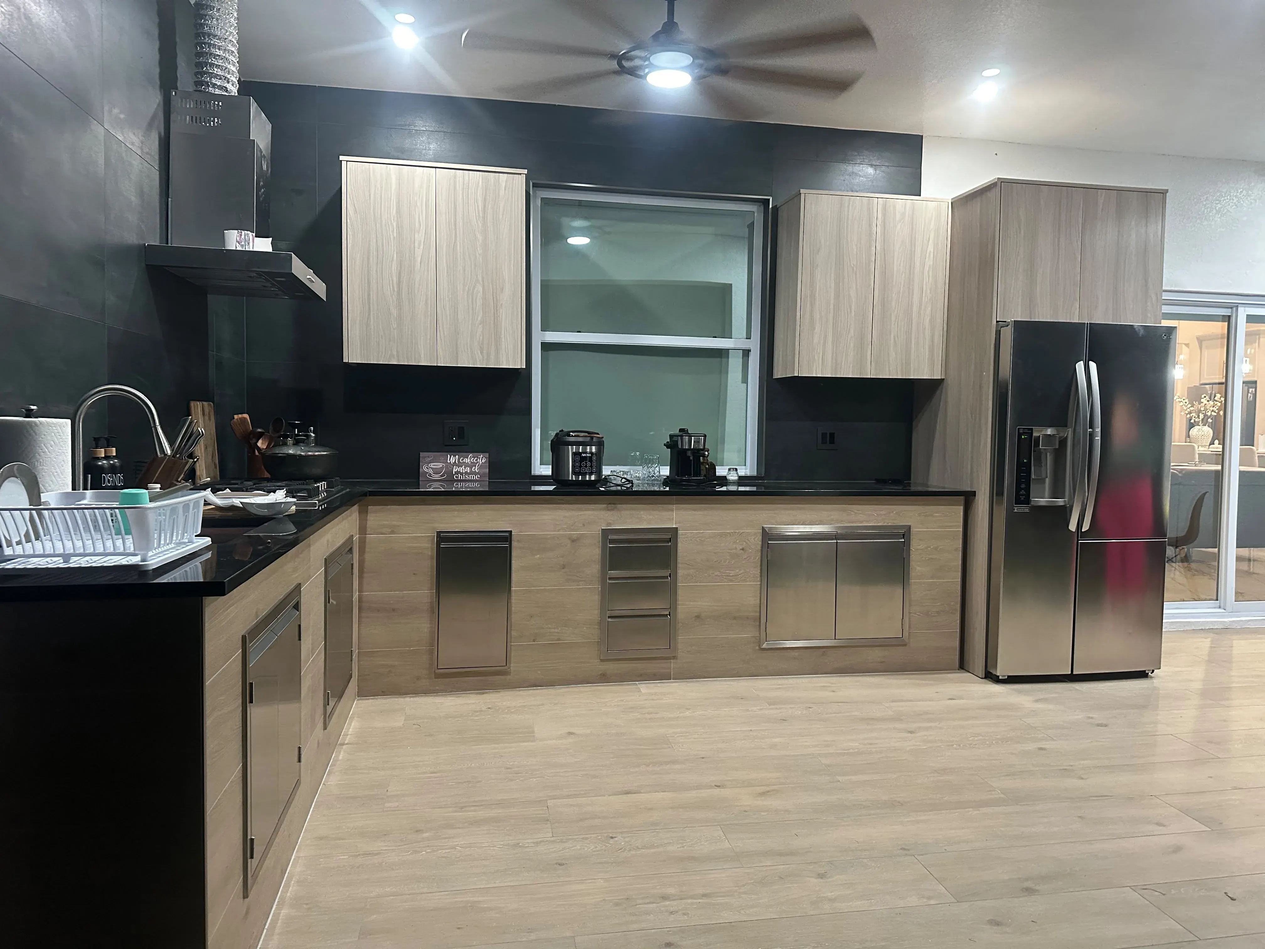Two-tone wood and black kitchen with a stainless refrigerator