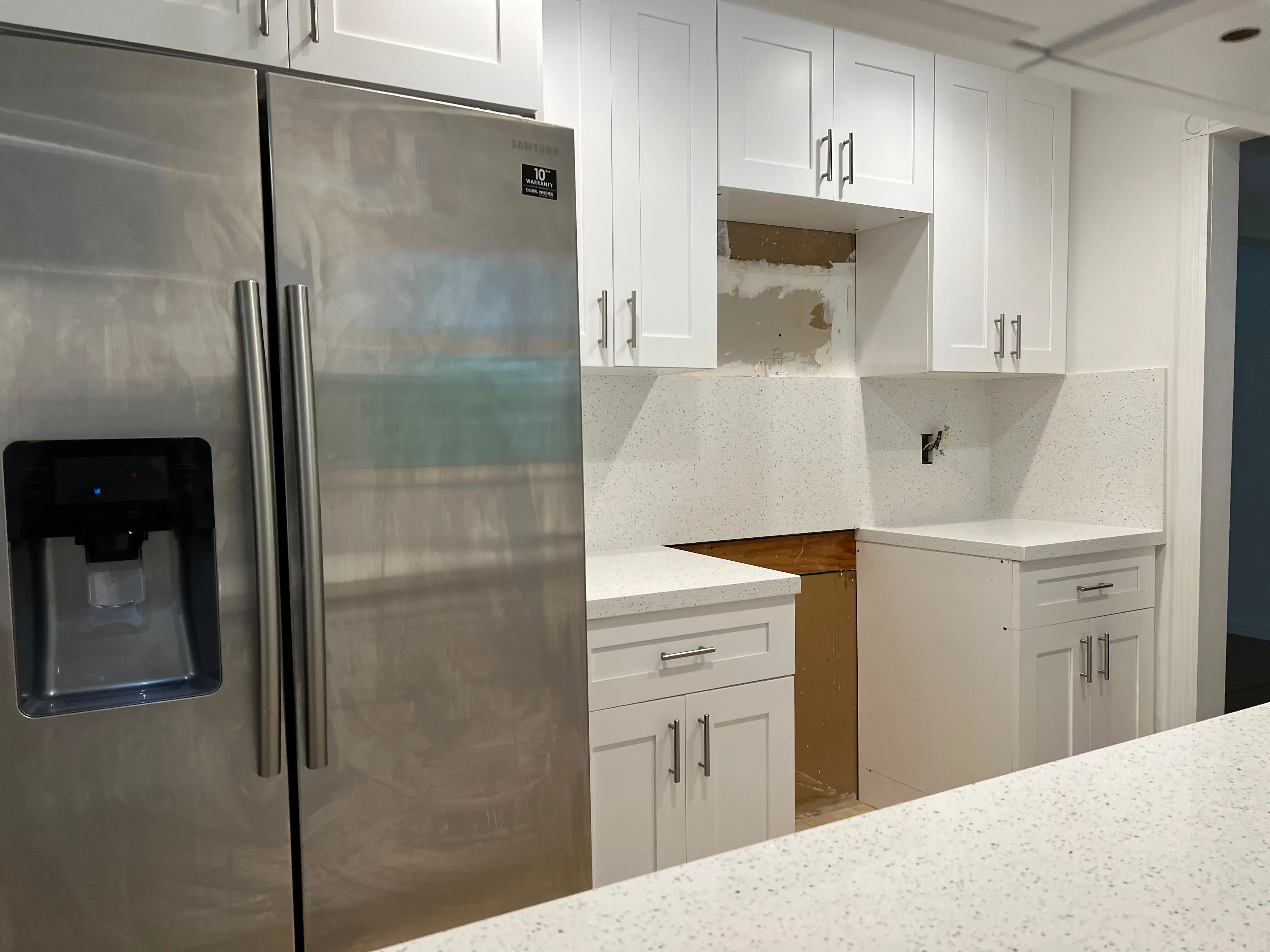 White shaker cabinets next to a stainless steel refrigerator