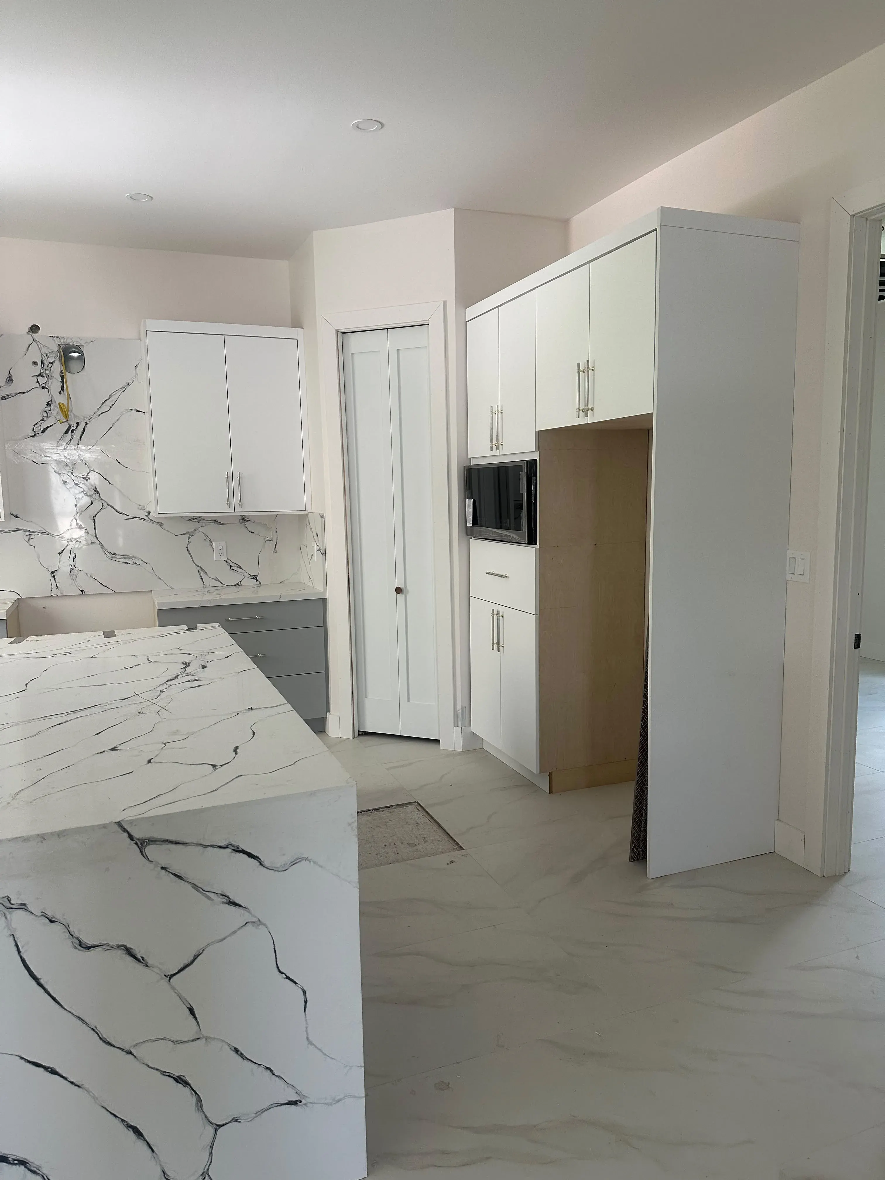 Kitchen with white cabinets and a marble island