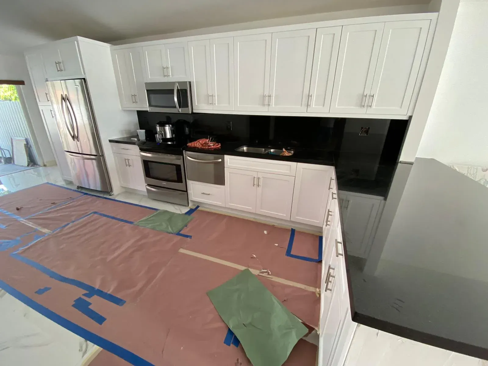 White shaker kitchen cabinets with protective floor covering