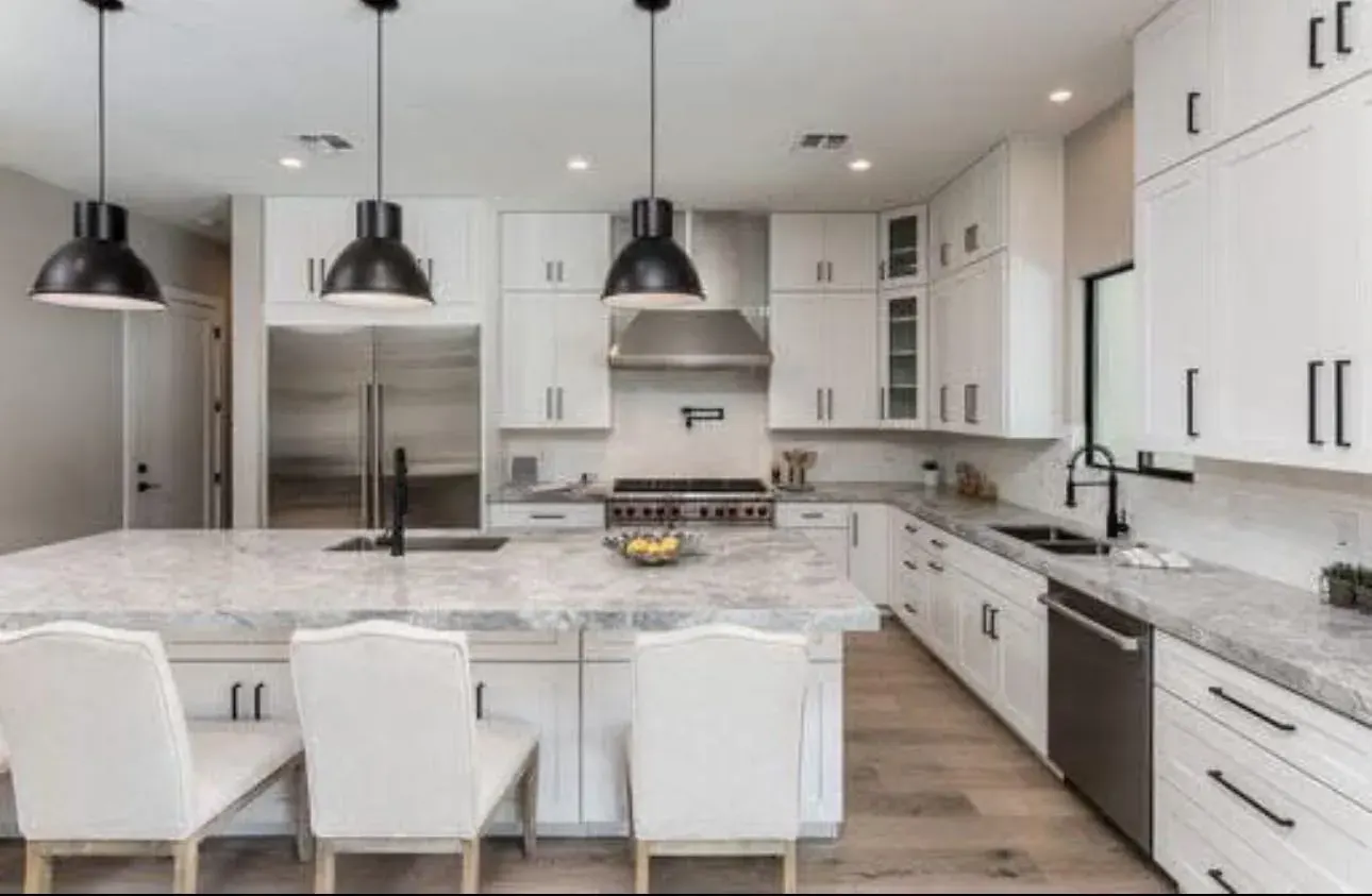 White shaker kitchen with pendant lights, a large island and bar stools
