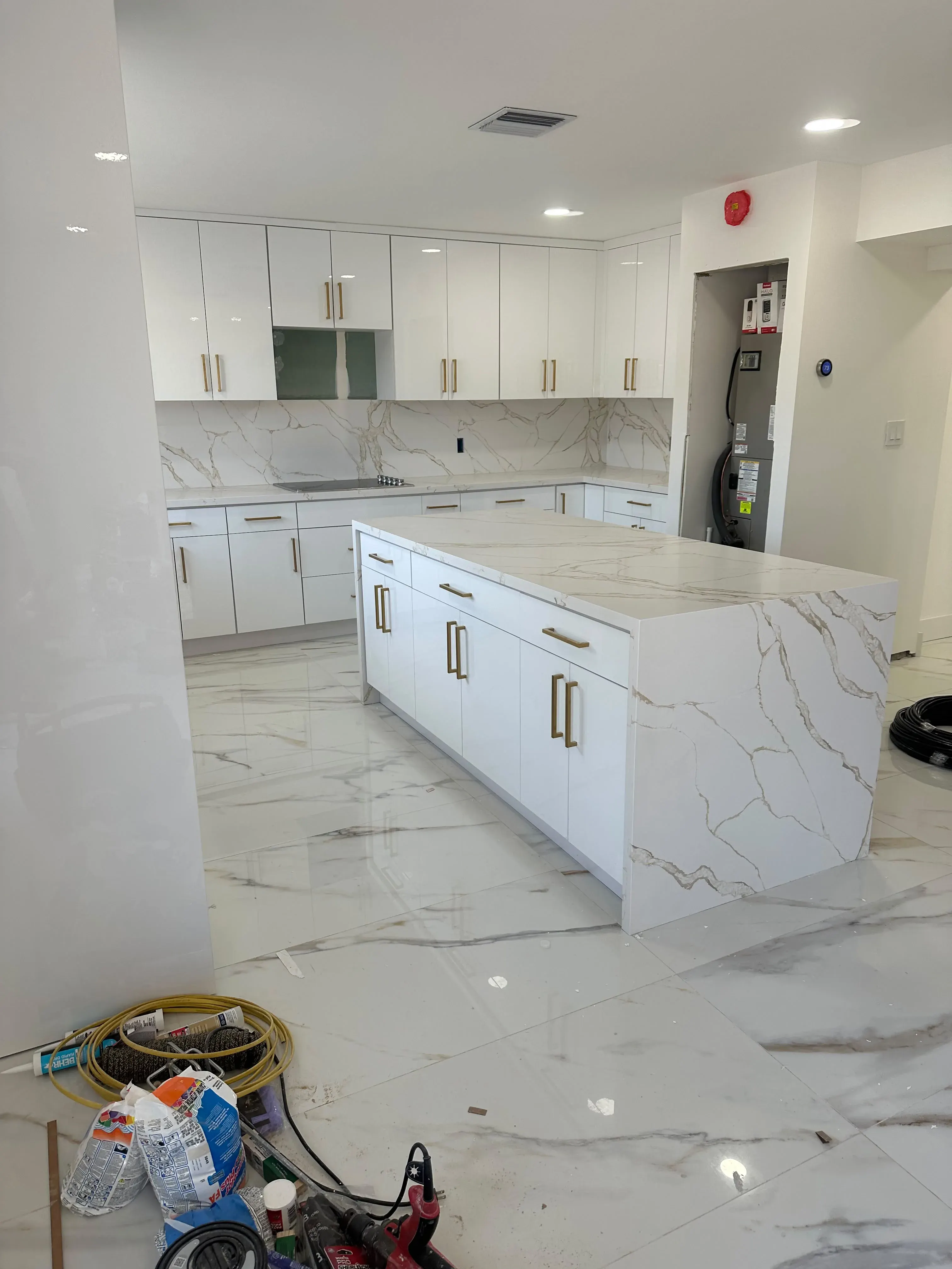 White kitchen with an island and marble floor