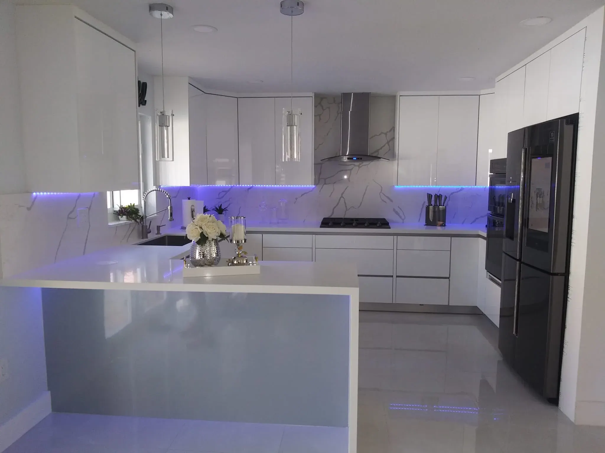 White glossy kitchen with LED lighting and a waterfall peninsula