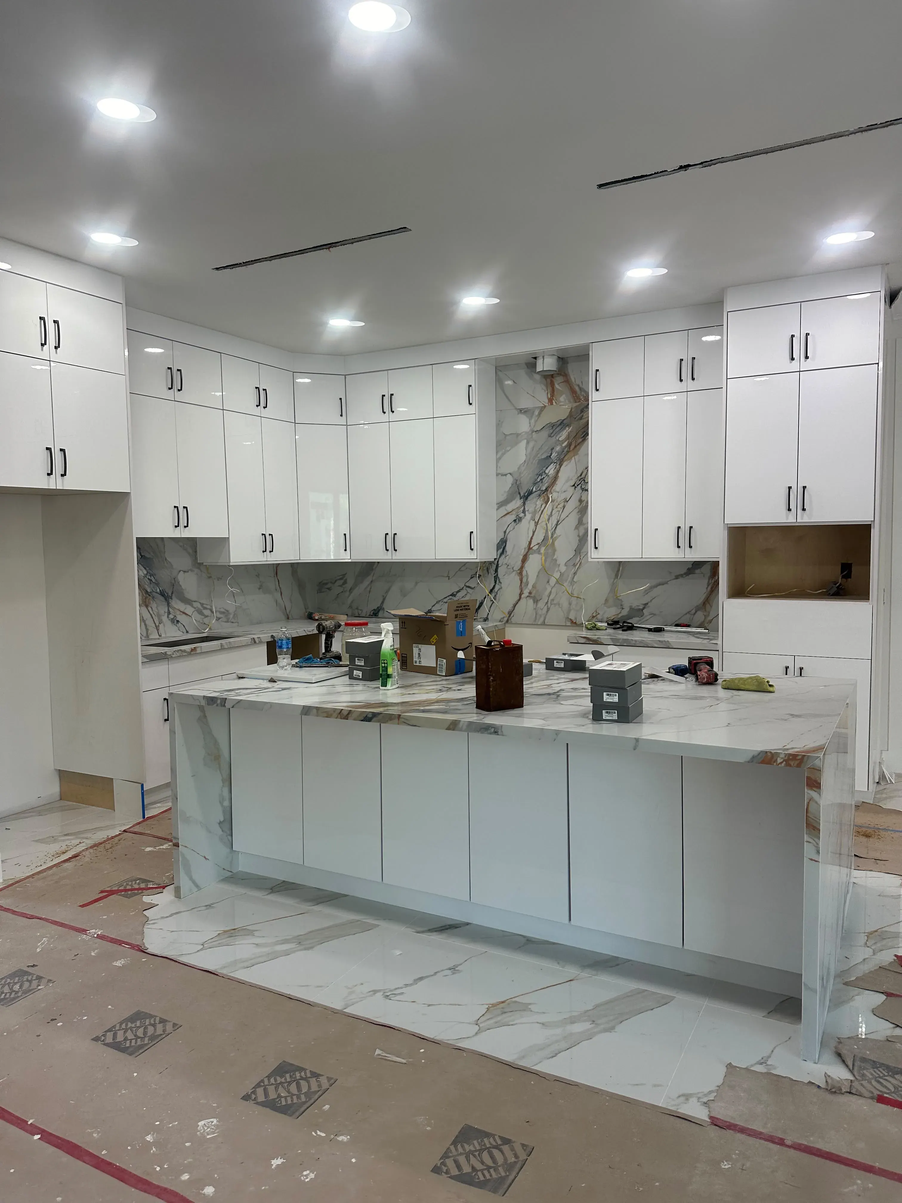 Kitchen island and cabinets with a marble backsplash during installation