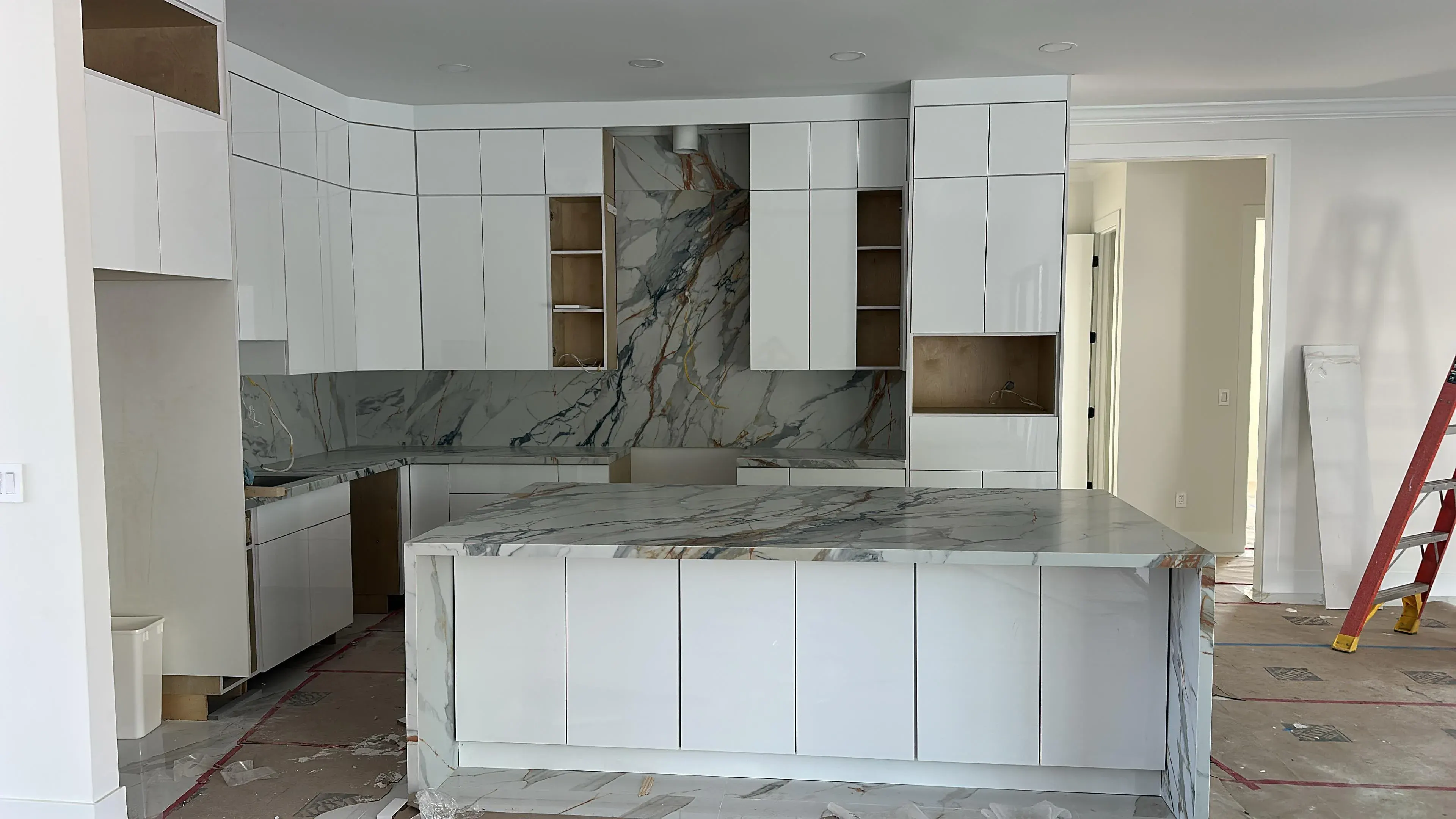 White kitchen with a marble backsplash and island under construction