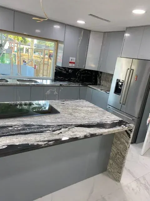 Gray cabinets with a granite countertop and waterfall edge