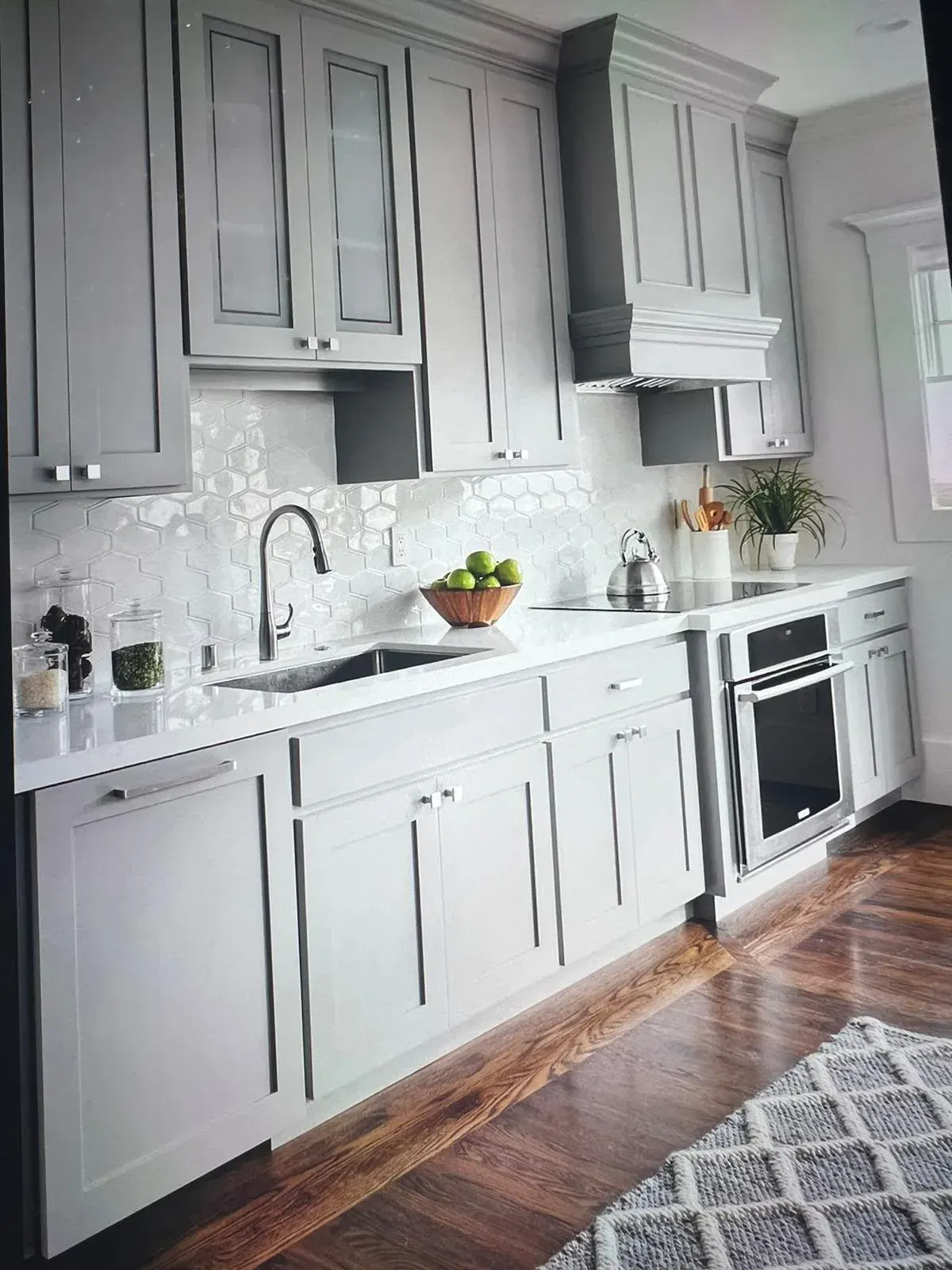 Gray shaker cabinets with a decorative range hood and white backsplash
