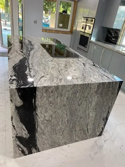 Granite waterfall island with a built-in cooktop
