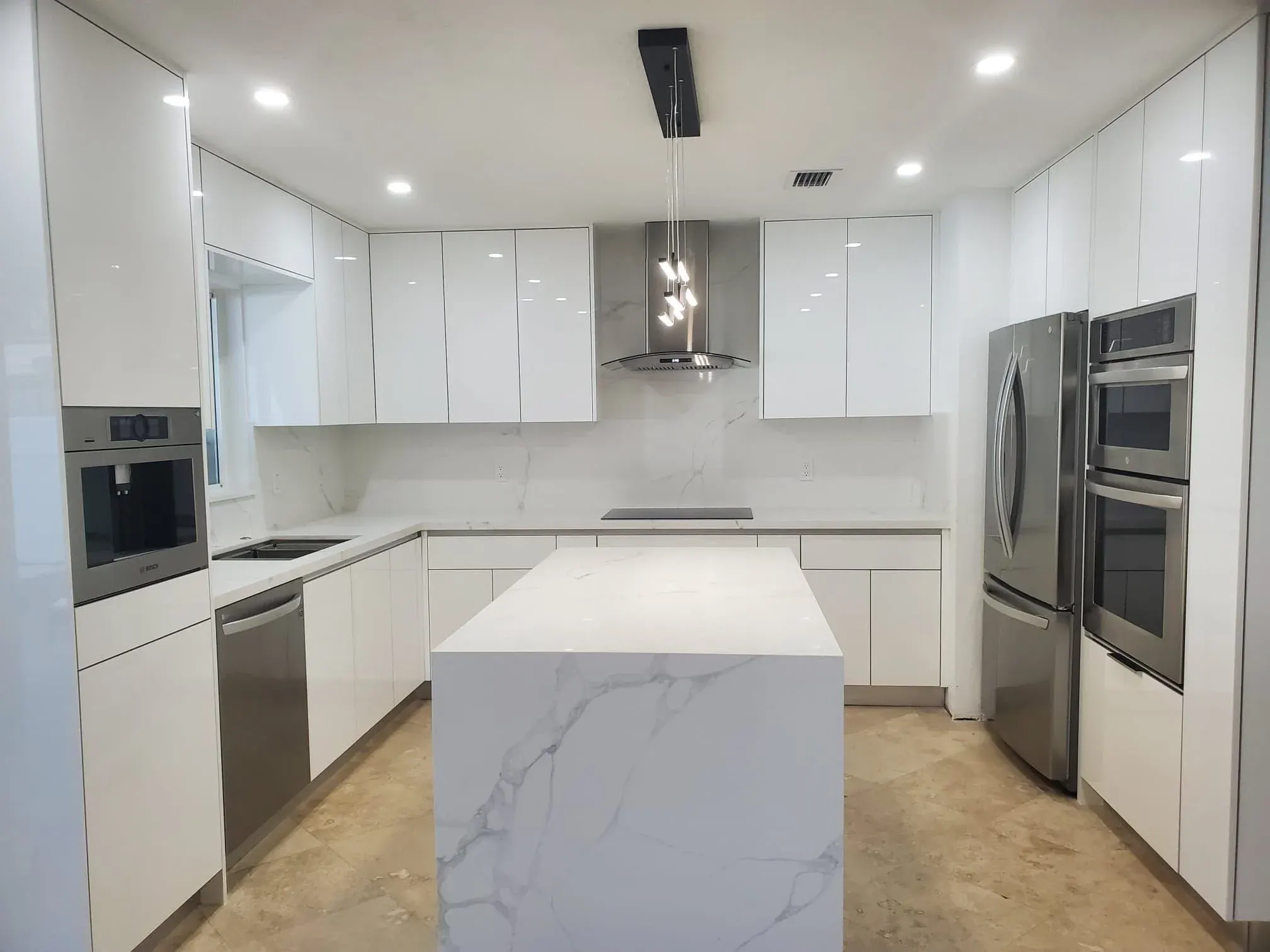 White high-gloss custom kitchen cabinets with a marble island, built and installed by Contrera Cabinets