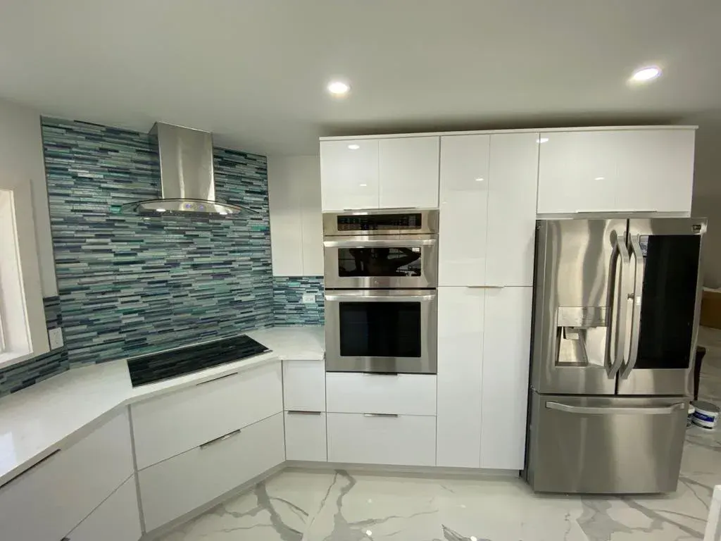 White cabinets with a blue glass tile backsplash and double ovens