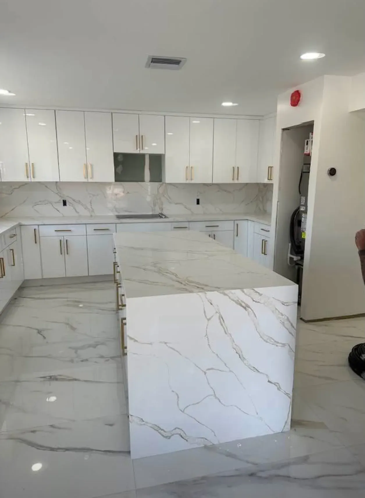 White kitchen with a marble island and gold hardware