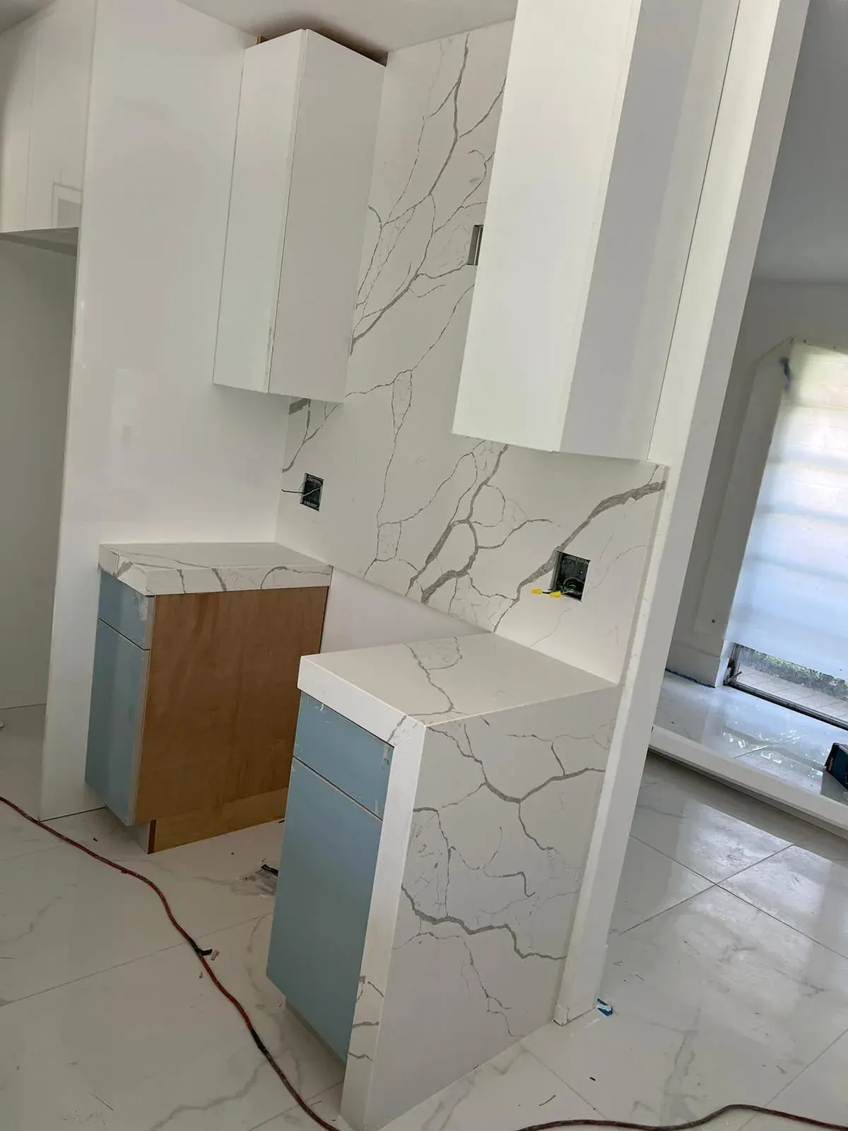 White and blue cabinets with a marble countertop in progress