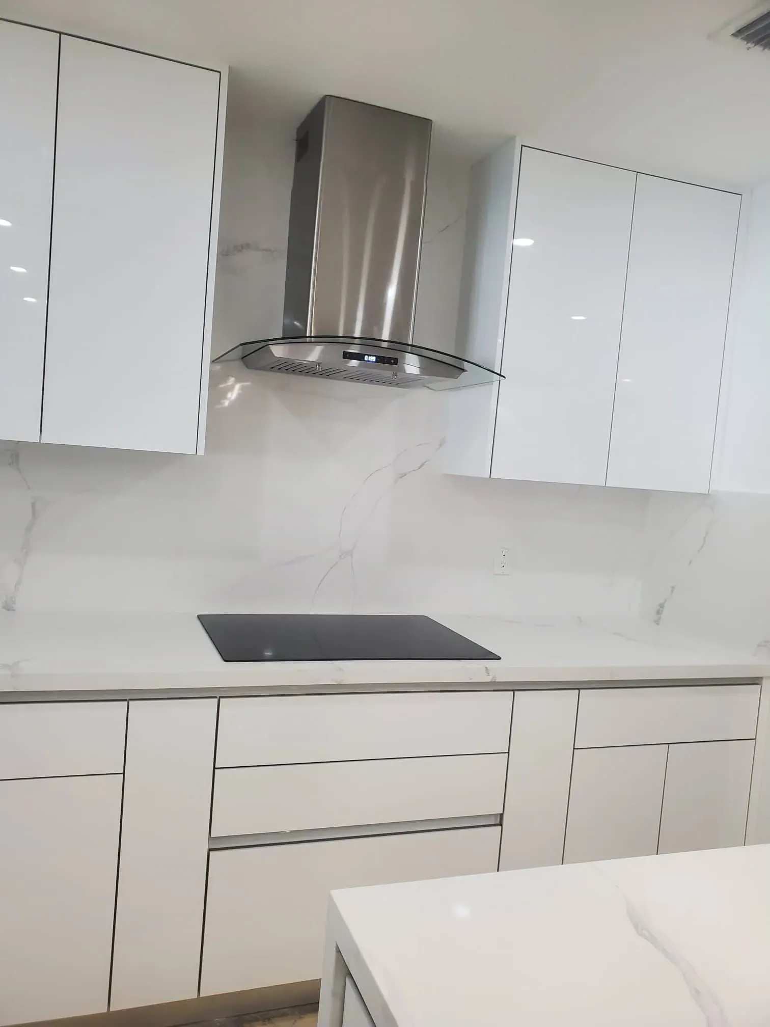 White high-gloss cabinets with a range hood and induction cooktop