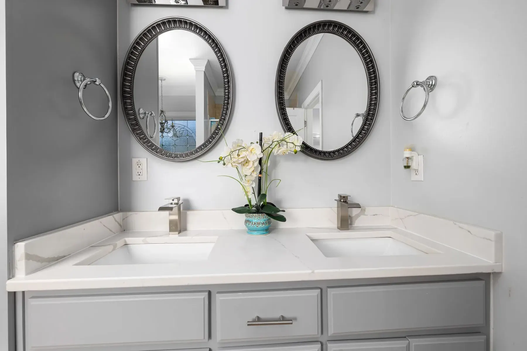 Gray double bathroom vanity with oval mirrors in a remodeled bathroom