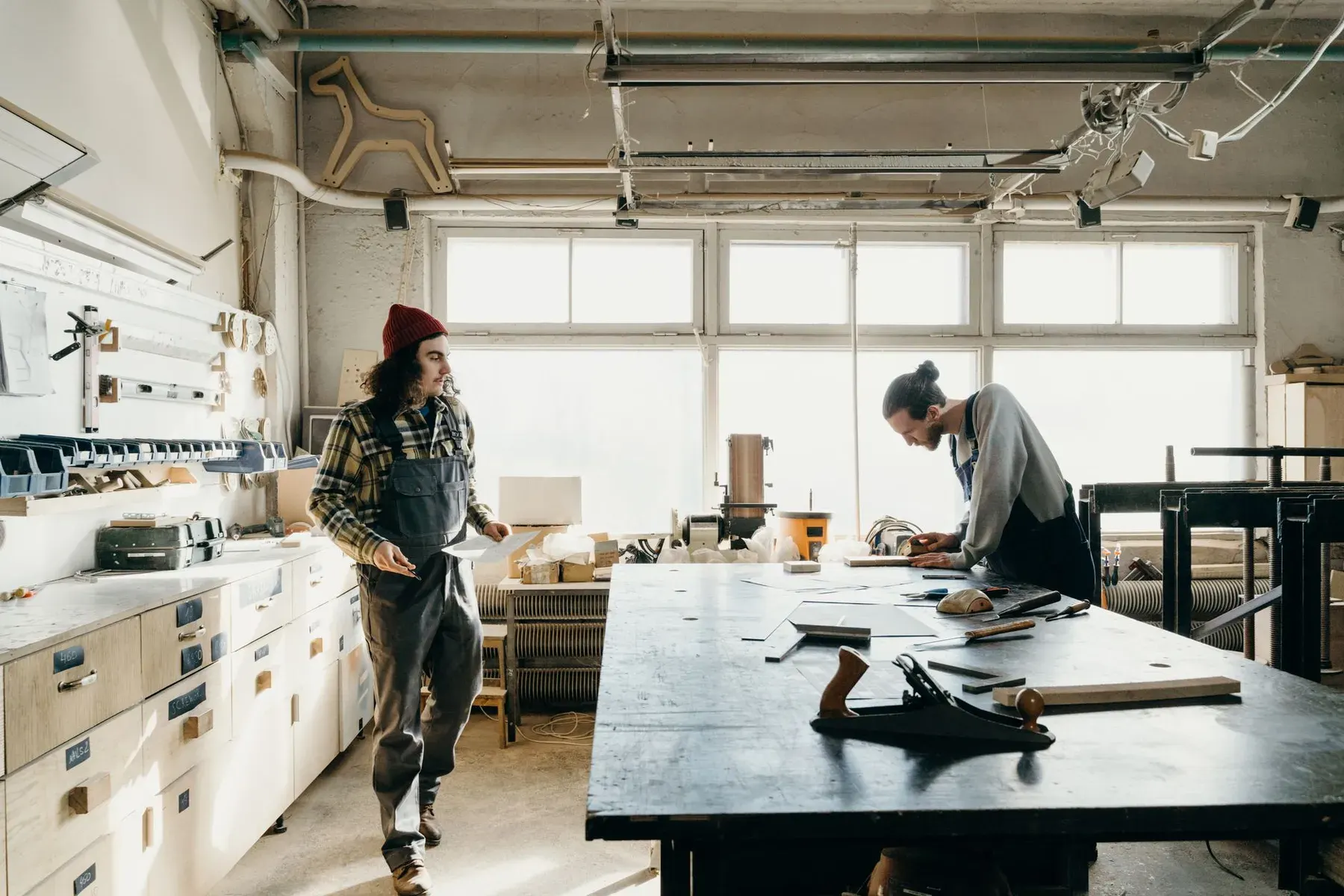 Two woodworkers in a sunlit cabinet workshop in Lehigh Acres